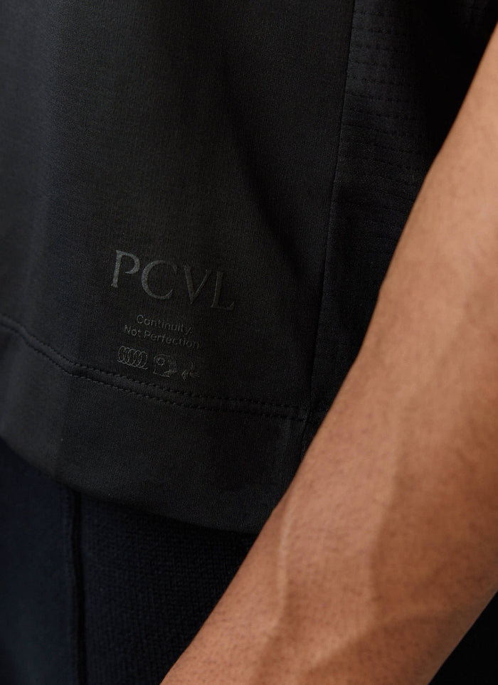 Close-up of the tonal black 'PCVL Continuity Not Perfection' branding on the Percival Performance T-Shirt.