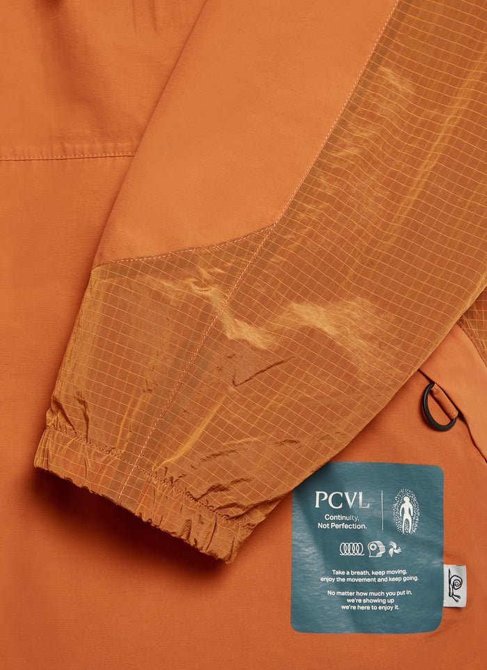A close-up of the Percival PCVL jacket in rust, highlighting the contrast panel sleeve and Continuity, Not Perfection label.