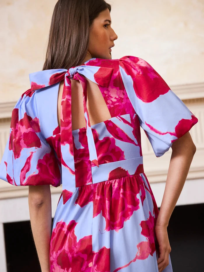 Woman wearing a red and white floral dress with a blurred background