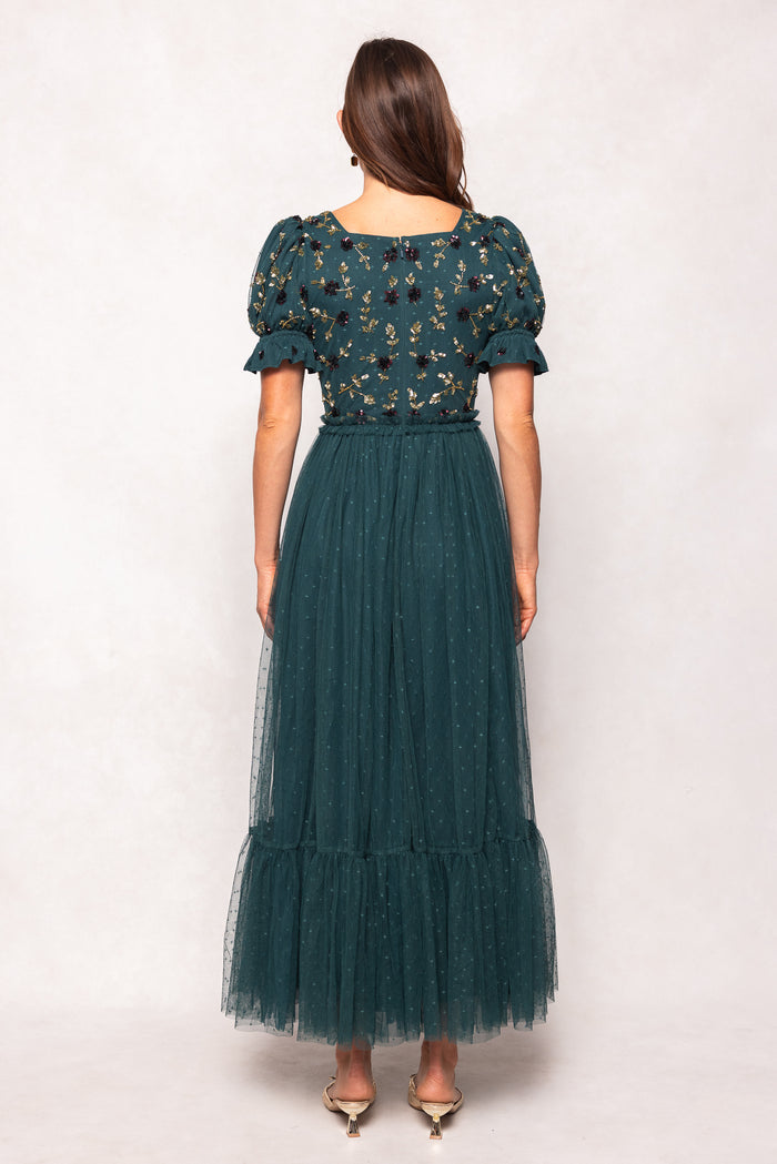 Woman wearing a green dress with floral patterns on a white background