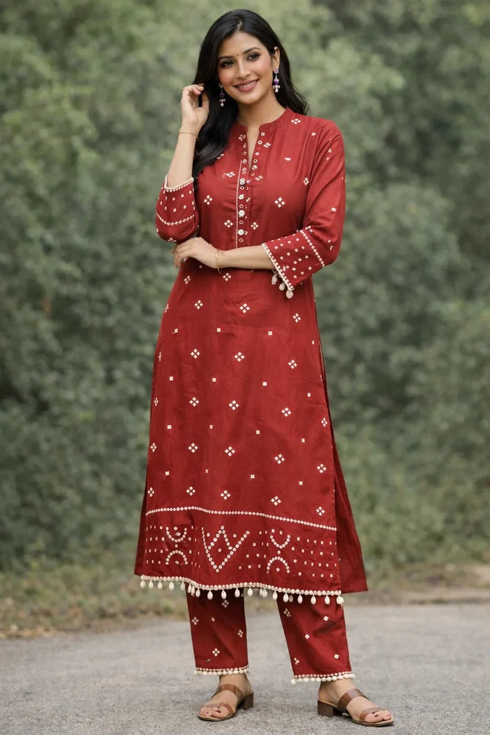 Woman wearing a red traditional outfit with white patterns against a green background