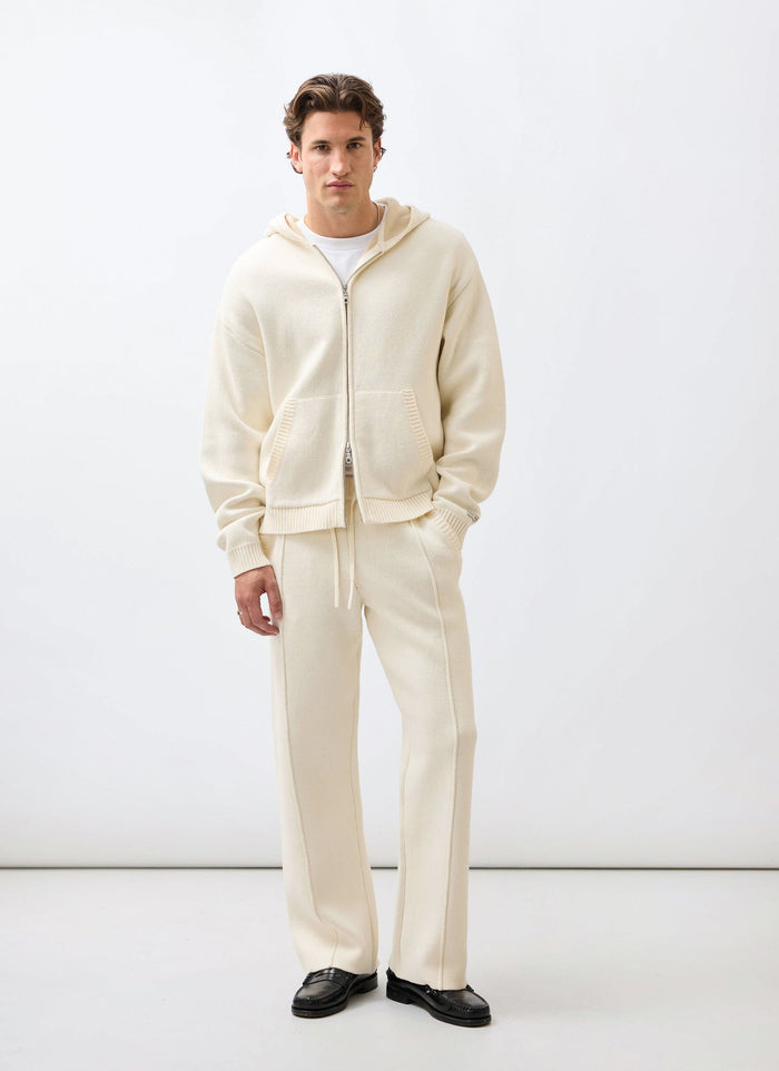 A model wears the Percival Chronicle co-ord set, featuring the ecru knitted straight-leg trackpants and matching zip hoodie.