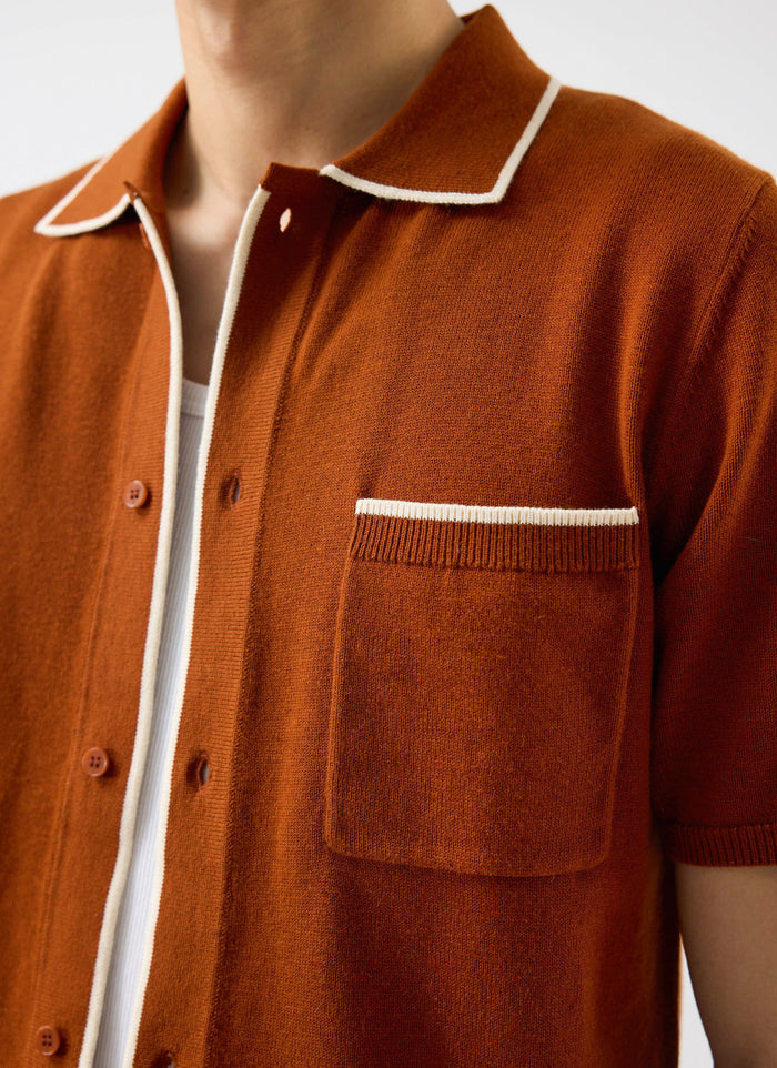 A close-up of the Percival Contrast Trim Shirt in rust, showing the wool-blend knit and white trim on the collar and pocket.