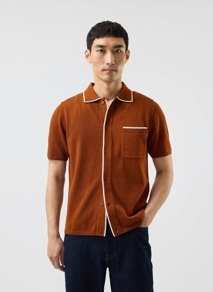 A model wears the Percival Contrast Trim Shirt in rust, a wool-blend knit styled with dark denim jeans.