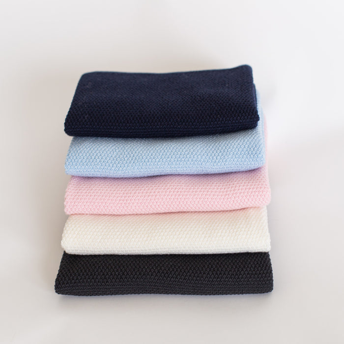 Stack of different coloured baby blankets.