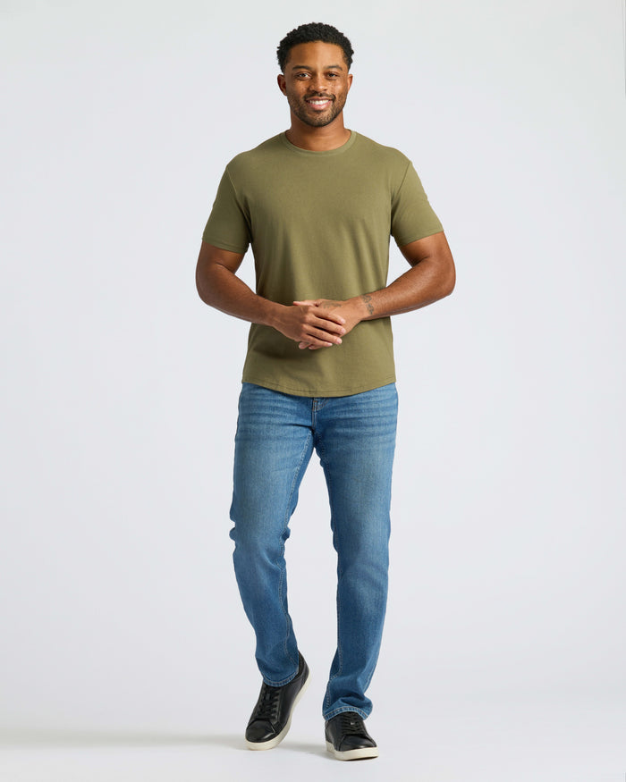Man wearing a Military Green Curved Hem Classic Crew Neck and slim-fit jeans.