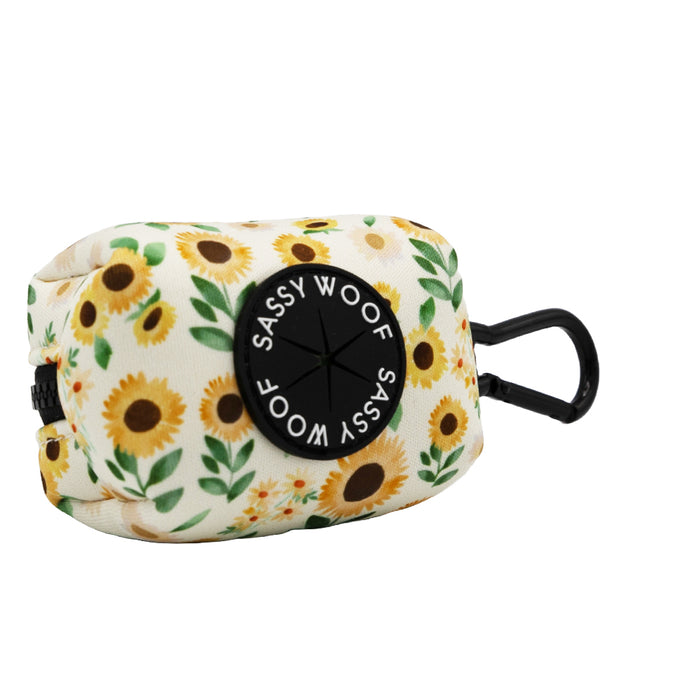 Carry waste bags in style with this rectangular pouch featuring a cheerful sunflower pattern, a black plastic clip, and a distinctive black circle emblazoned with "Sassy Woof" in white text. This waste bag holder is the ideal accessory to pair with your Sassy Woof Dog Collar Three Piece Bundle - Sunflower Dreams.