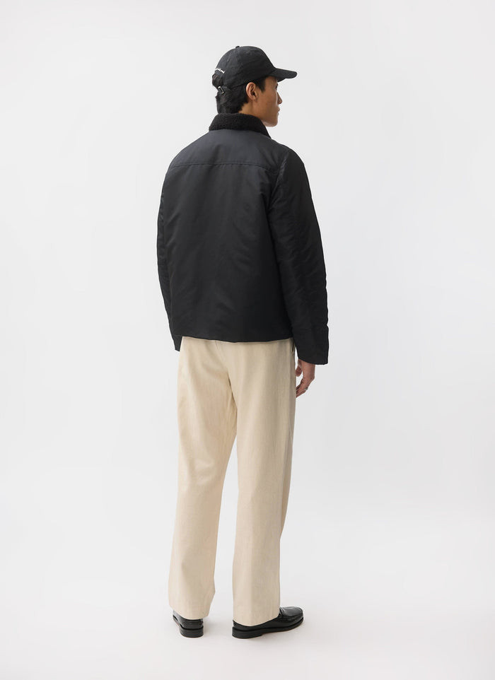 A model, seen from behind, wears the black Percival Doppio Bomber Jacket with its faux shearling collar.