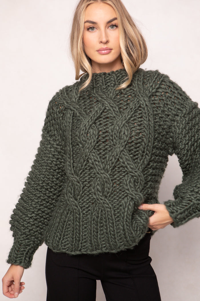 Woman wearing a green knitted sweater against a plain background