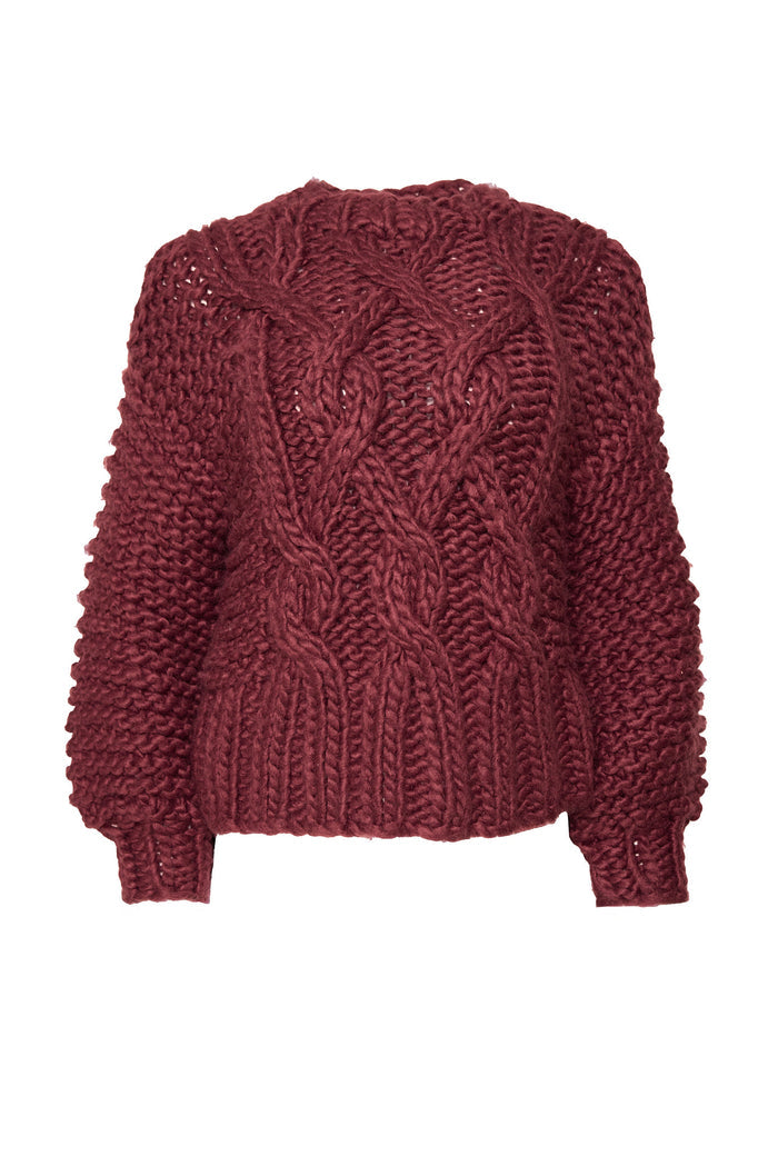 The Erica Sweater in Raisin by Ivy City Co is a chunky cable knit, long-sleeved sweater with thick front patterns and ribbed cuffs and hem. Displayed on a white background, it's cozy and maternity friendly.