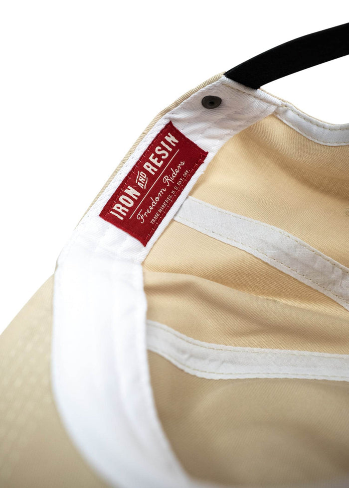 Close up of tan cotton twill hat with custom woven tag, leather strap and durable construction