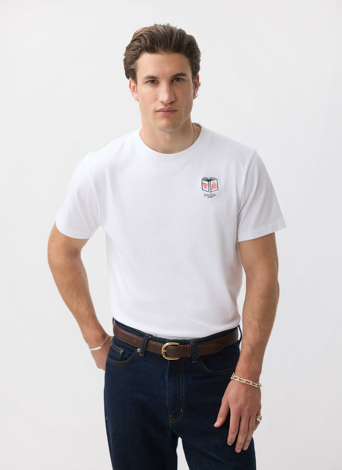 A model wears the white organic cotton Greatest Bookshop T-shirt from Percival, featuring an embroidered book on the chest.