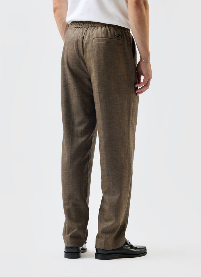 A model seen from behind wearing the Percival Grounds Relaxed Trousers in Oak herringbone wool, styled with loafers.