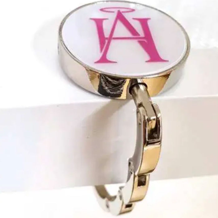 Round handbag hook with pink HA logo on a polished silver finish.
