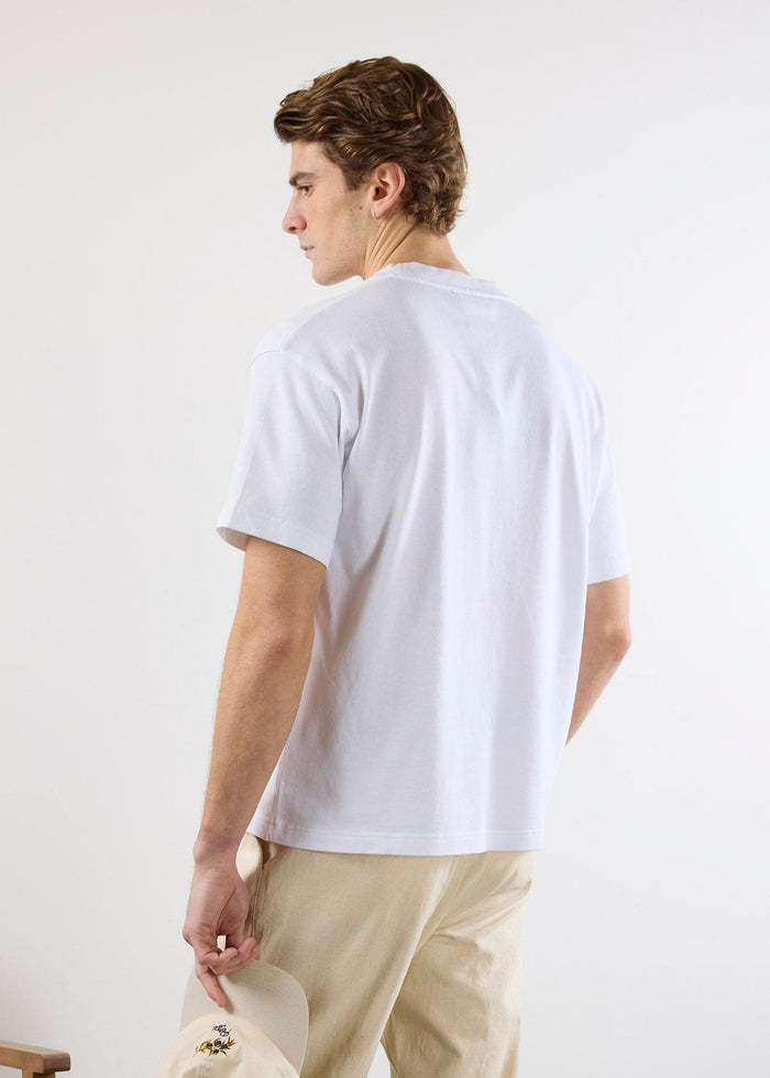 Back view of a model wearing the white Percival Iced Matcha oversized t-shirt, styled with beige trousers.