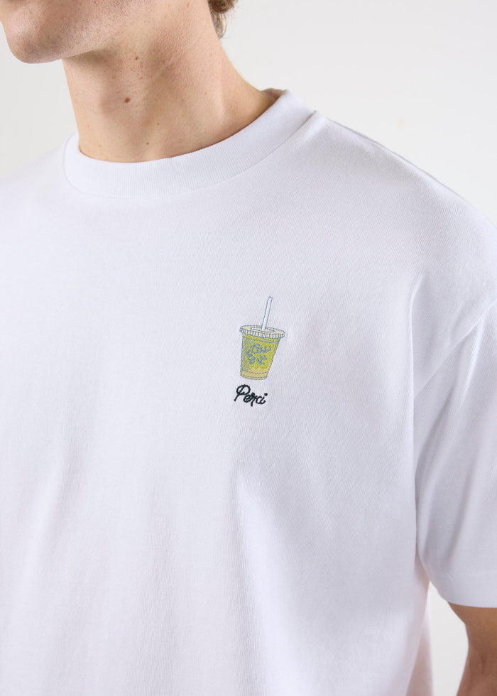 A close-up of the embroidered iced matcha graphic on the chest of the white organic cotton t-shirt from Percival.