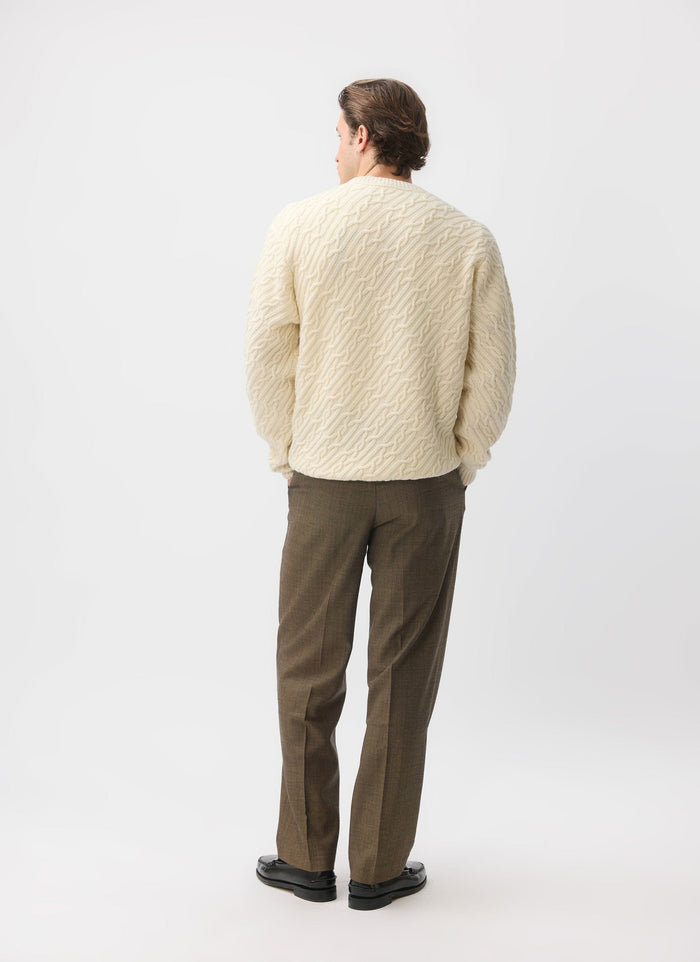 A model seen from behind wearing the Percival Melville Cable Knit Jumper in ecru, showcasing its diagonal knit pattern.