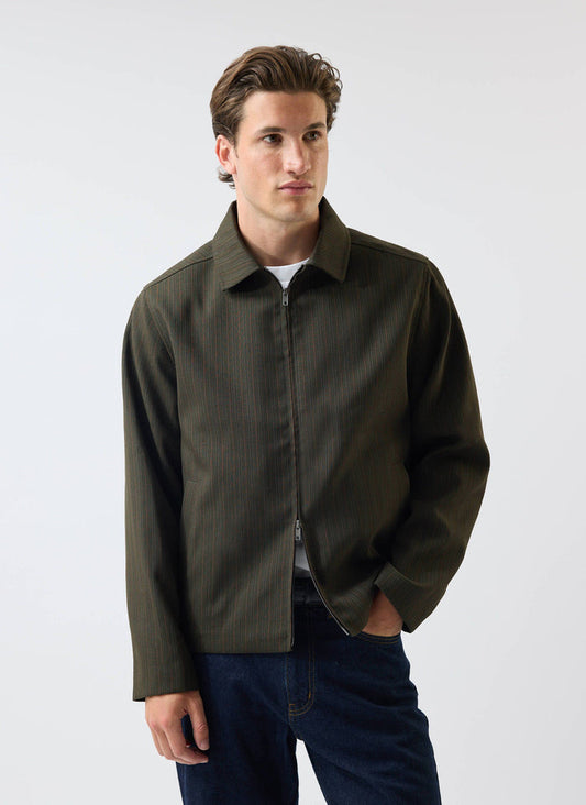 A model wears the Percival Chapter Zip Up Jacket in forest green, styled with a white t-shirt and dark blue jeans.