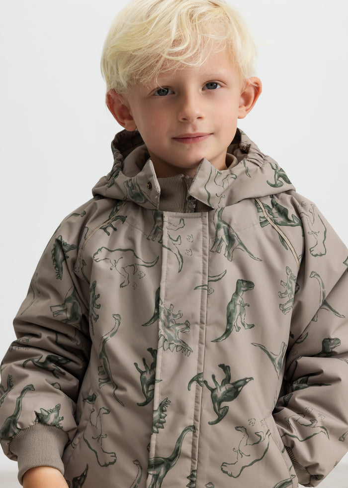 Børnevinterjakke i beige med dinosaurprint og hætte, set på barn