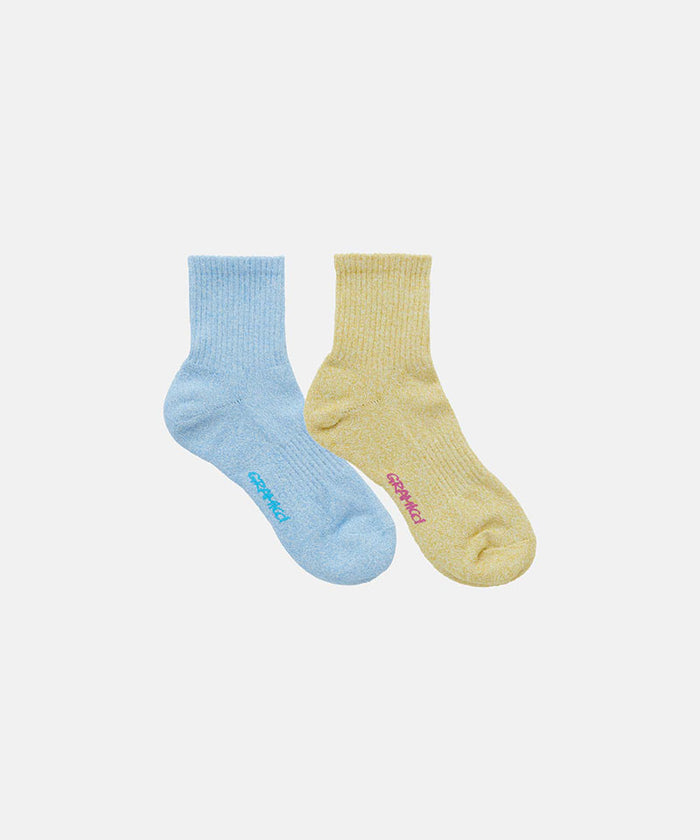 Sky blue and yuzu yellow Gramicci Paper Mix Socks against a light-tone background.