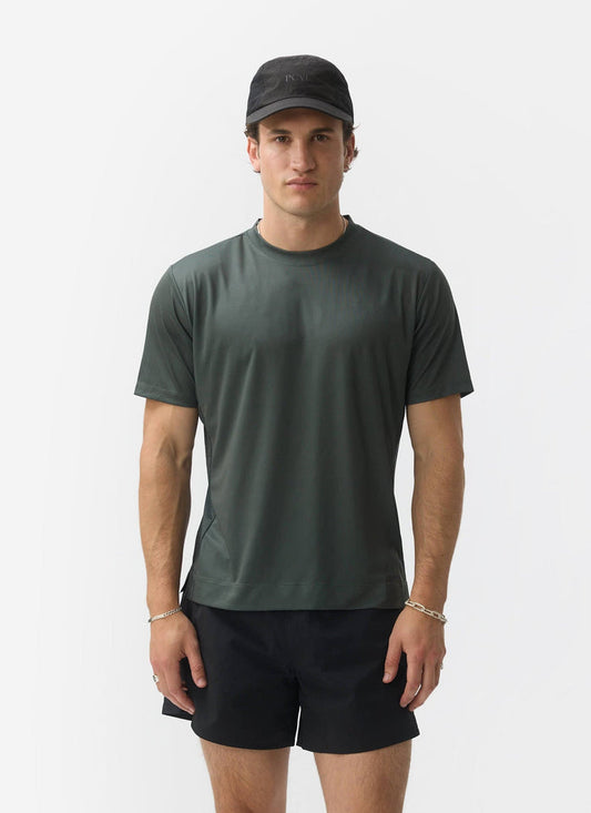 A model wears the Percival PCVL Performance Top in Forest green with black shorts and a cap against a white background.