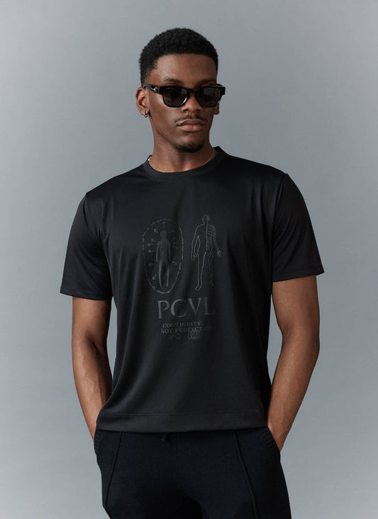 A model wears the black PCVL Printed Performance T-Shirt from Percival, showing the subtle black-on-black graphic print.
