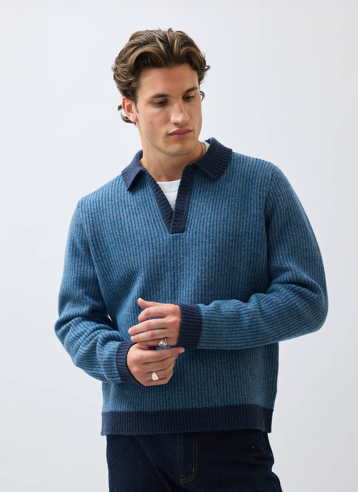 A model wears the Percival Picnic Polo, a two-toned blue ribbed knit with a contrasting navy collar, cuffs, and hem.