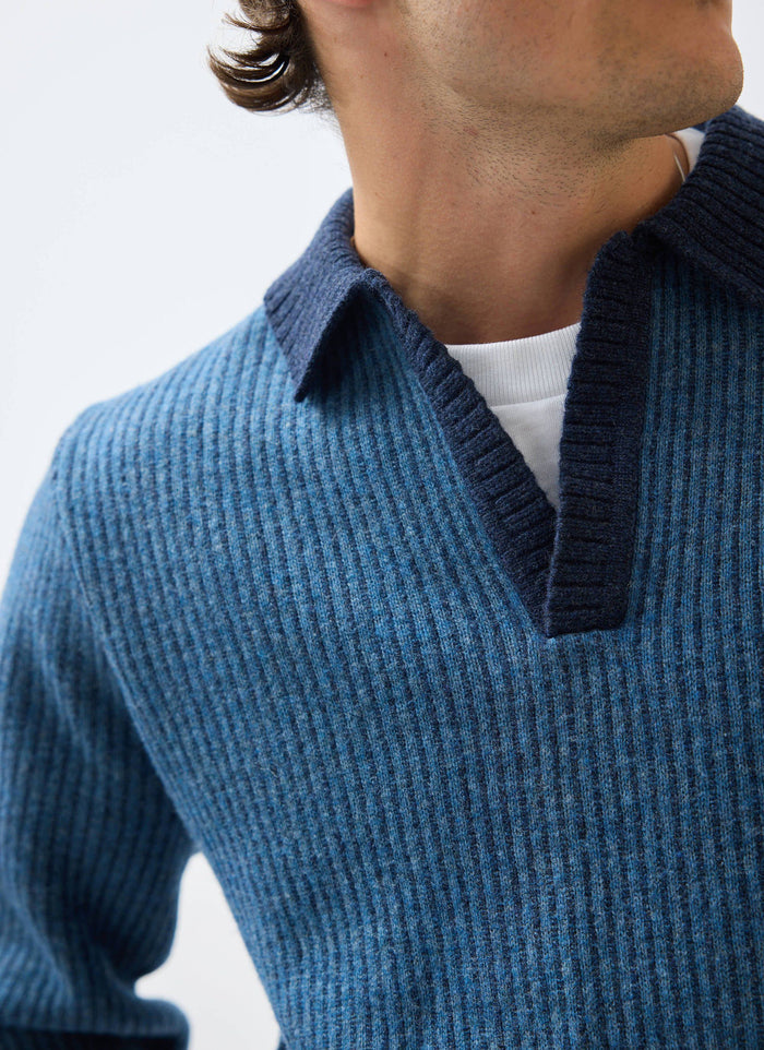 A close-up of a model wearing the Percival Picnic Polo in navy, showing the two-toned ribbed knit and collar detail.