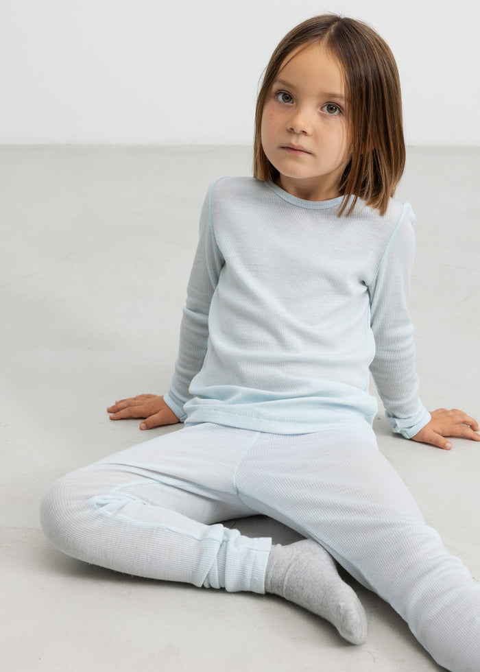 Child wearing light blue t-shirt and merino wool leggings