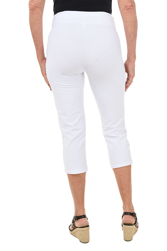 A back shot of a model wearing a pair of white pull-on slimming capri pants with a mesh tummy control panel.