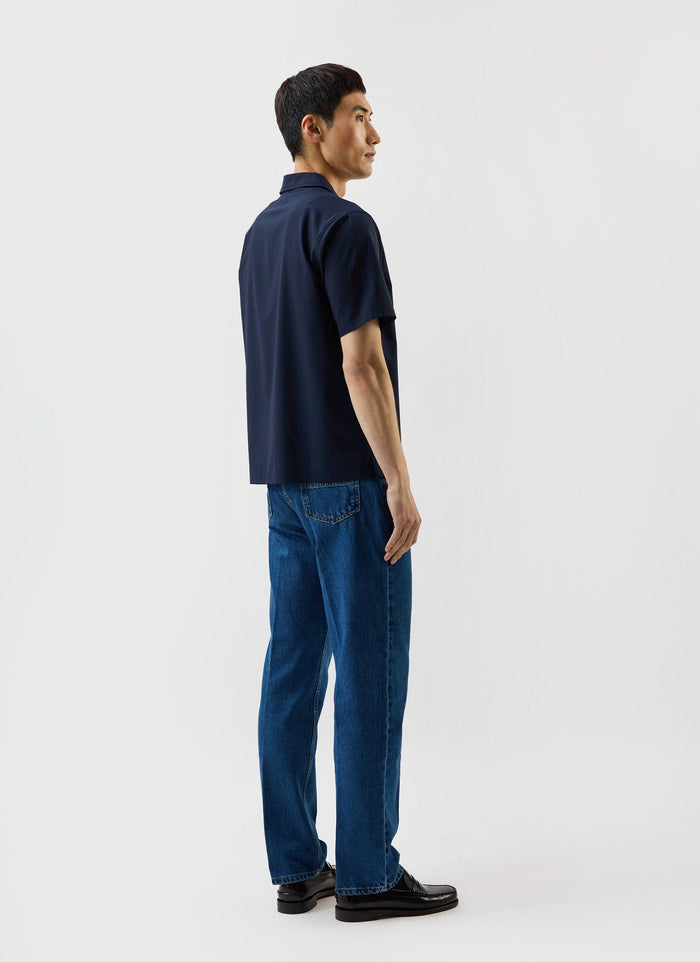 Rear three-quarter view of a model in the Percival x Warren Relaxed Cuban Drape Shirt in navy blue, styled with jeans.