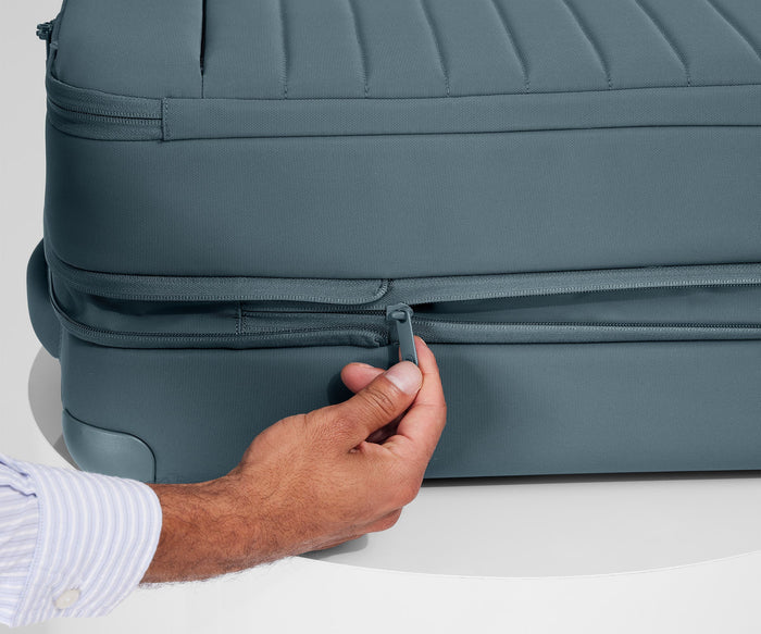 Person expanding the bag, using the wraparound zipper // An additional wraparound zipper allows you to easily expand
