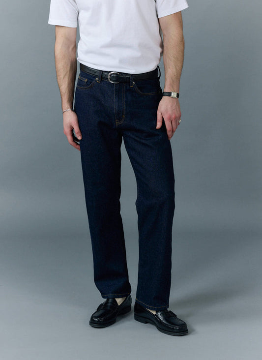 A model wears the Percival Straight Leg Denim Jeans in dark indigo, styled with a white t-shirt and black loafers.