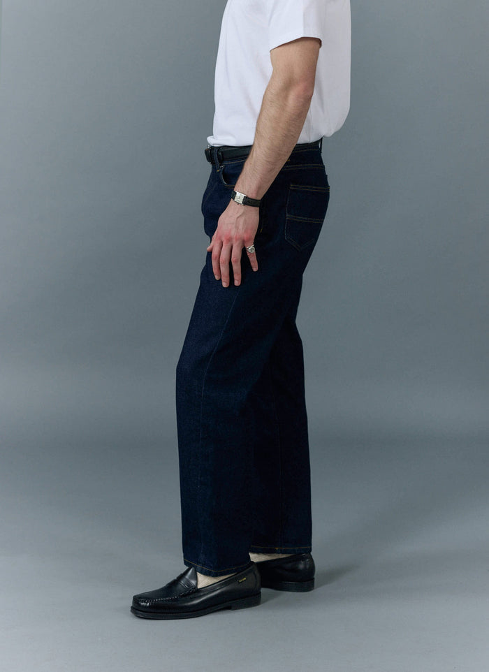 A model wears the Percival Straight Leg Denim Jeans in Dark Indigo, showing the classic straight leg fit from the side.