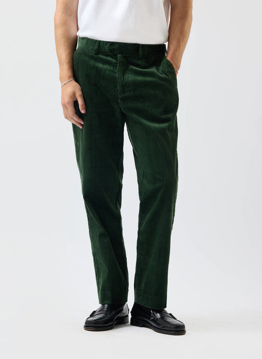 A model wears the Percival Tailored Chunky Cord Trousers in forest green with a white t-shirt and black loafers.