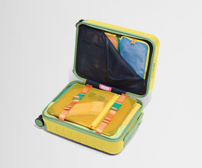 The Kids Carry-On suitcase in Sunshine Yellow shown open on its side and packed with Away's packing organizers to show capacity and the interior compression system, designed to help you pack more in
// 
Our signature interior compression system allows you to stay more organized. Paired with the Kids Packing Cubes.