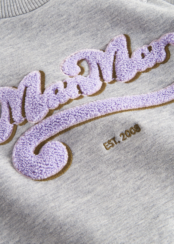 Detail of purple and gold embroidery on gray sweatshirt for children
