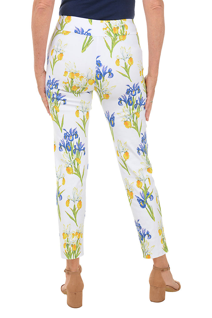 A back shot of a model wearing a pair of pull-on ankle pants with an elasticized waistband, featuring a white base with a blue and yellow floral pattern.