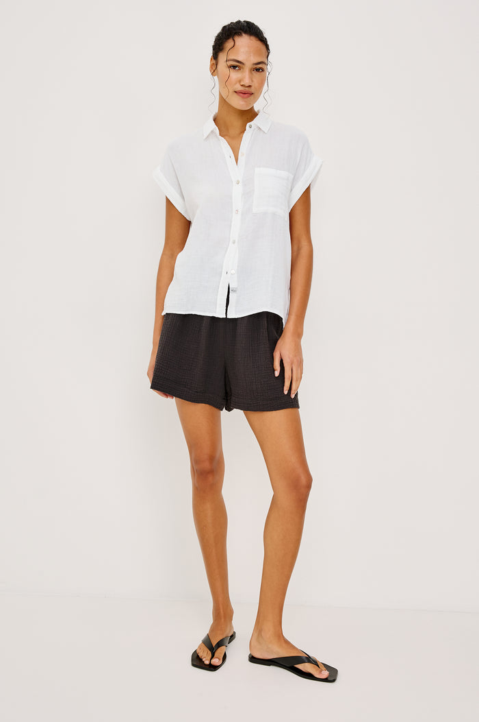 Whitney button front collared shirt with cuffed cap sleeve, features a chest pocket in white colorway. Front view featured on model